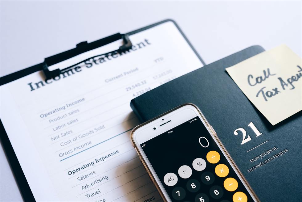 Income statement on a clipboard next to a phone calculator