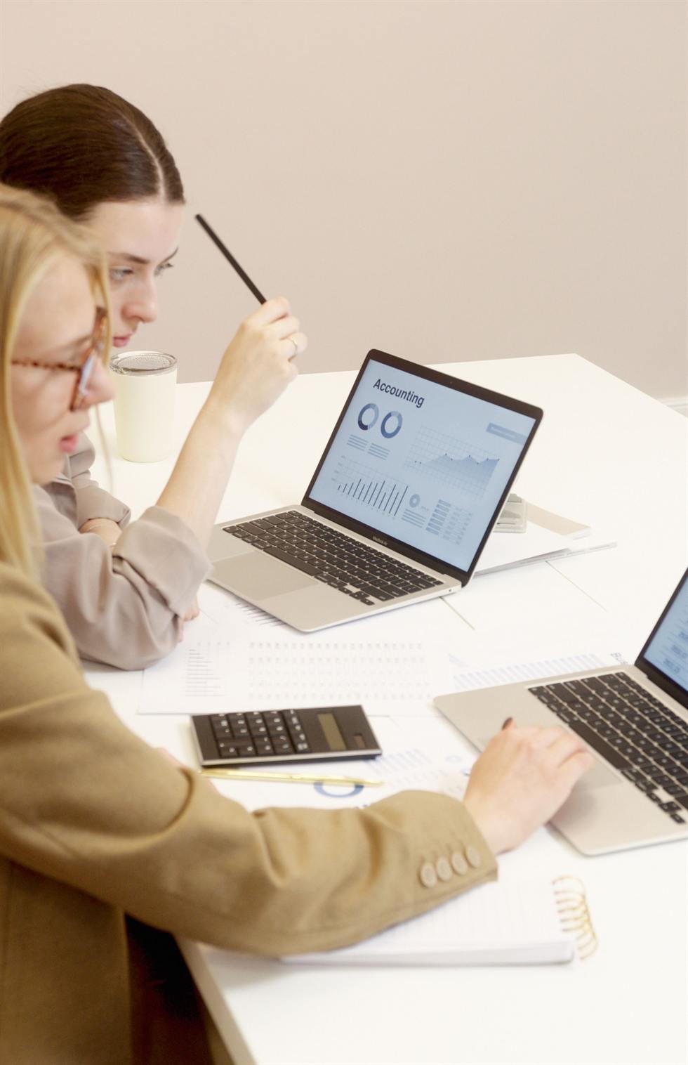 Two advisors reviewing an accounting dashboard on laptops