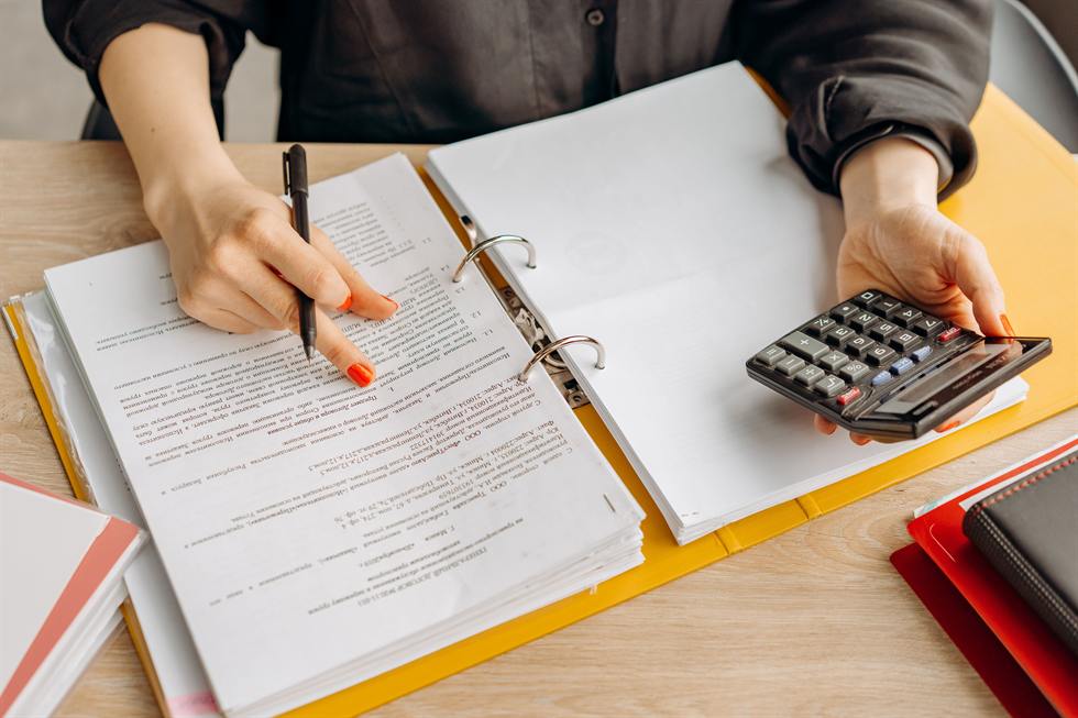 Reviewing a binder of tax case documents with a calculator in hand