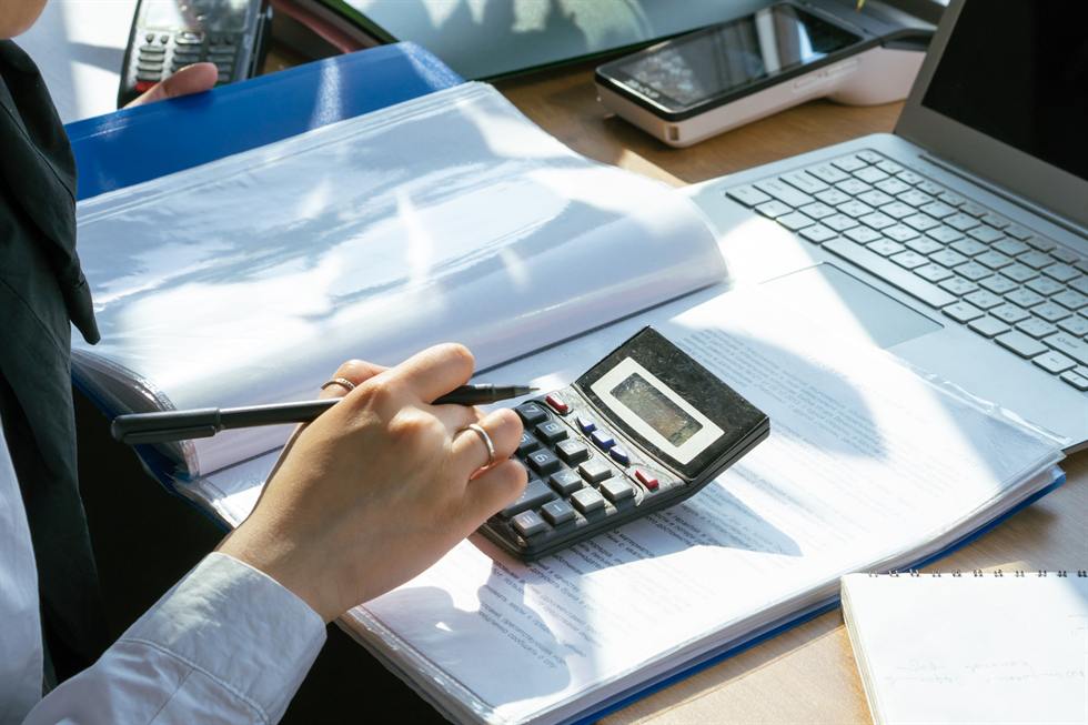 Processing payments at a desk with a calculator, card terminals, and a laptop