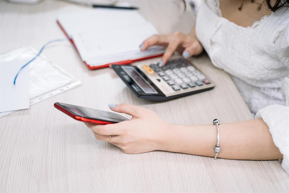 Working through numbers with a desk calculator and phone